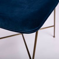 A blue Penelope side dining chair with the round back and large button detail combined with the saddle seat, closed up seat view.