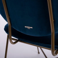 A blue Penelope side dining chair with the round back and large button detail combined with the saddle seat, closed up back view.