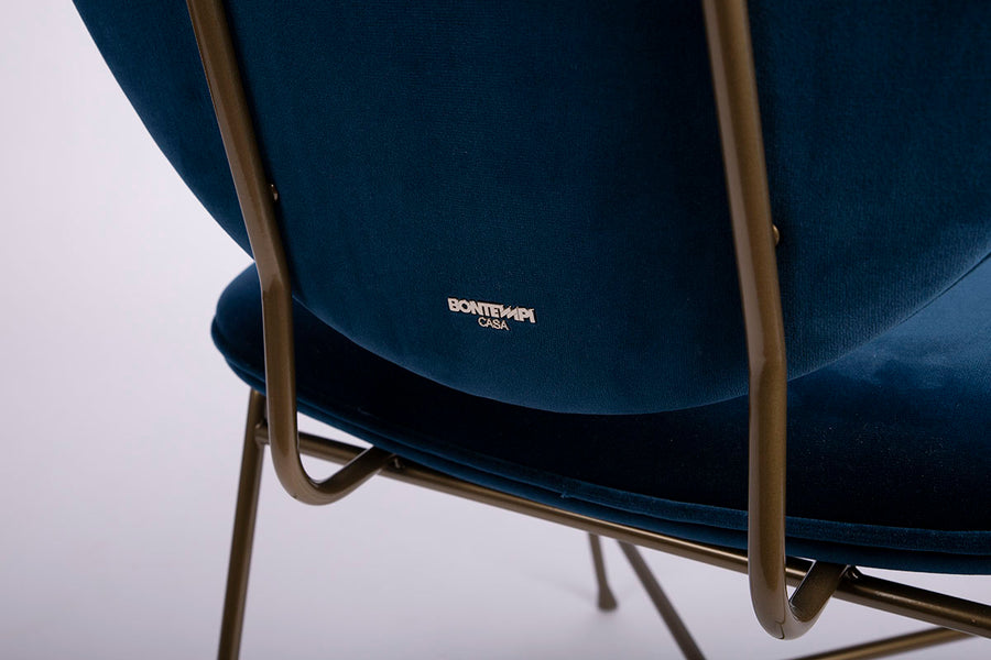 A blue Penelope side dining chair with the round back and large button detail combined with the saddle seat, closed up back view.