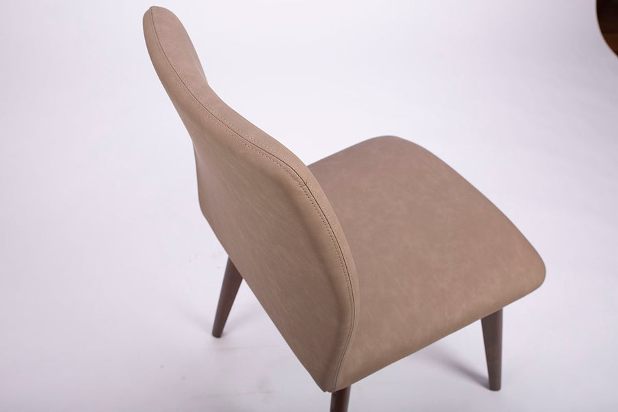 A beige Hexa swivel dining chair with wood base. Closed up top view.