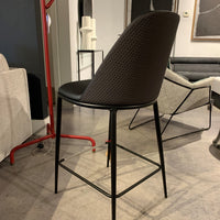 Black Lea counter stool with four-legs metal base and seat and backrest upholstered in hide. Back and side view.