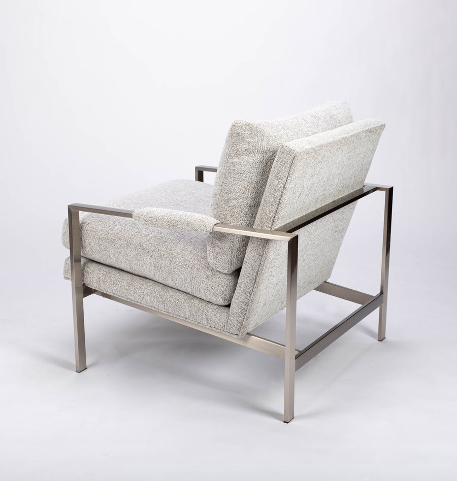 951 lounge chair in light colors with slender rectangular steel frame, luxurious blend down seating and upholstery wrapped arm rests, side view.