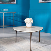 Reuleaux Large Cocktail Table with rounded, asymmetrical top and elegantly tapered legs, with a vase and flowers on it, placed in a room with blue walls.