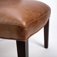 Goodman brown leather chair with curved back, textured woven fabric outside back. Closed up seat view.