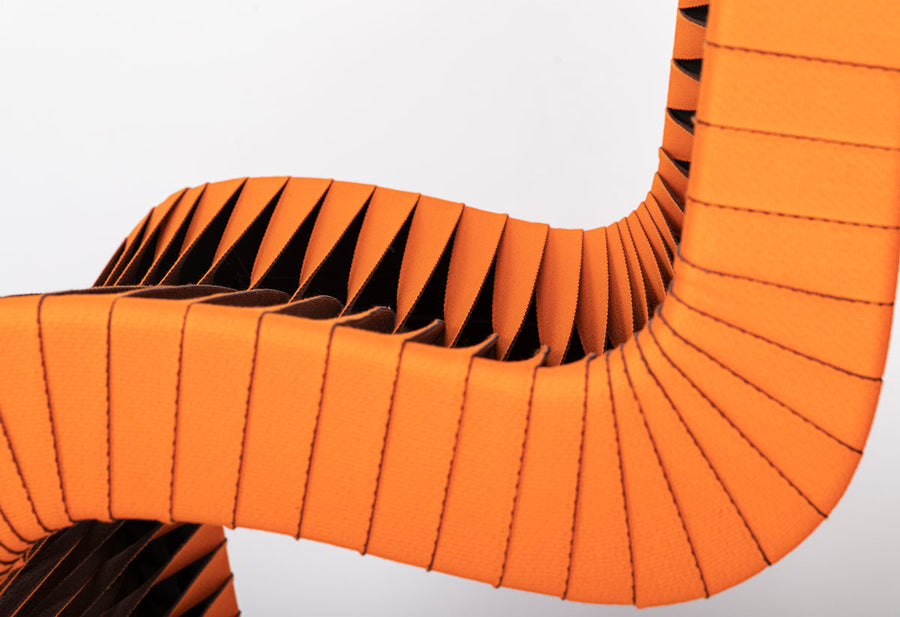 Orange and black Seat Belt dining chair with colorful seatbelt strappings, closed up side view.