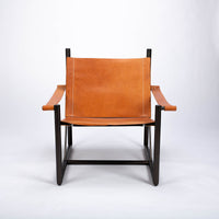 Pipe lounge chair with thick saddle leather strapped to striking metal frame, front view.