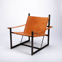 Pipe lounge chair with thick saddle leather strapped to striking metal frame.