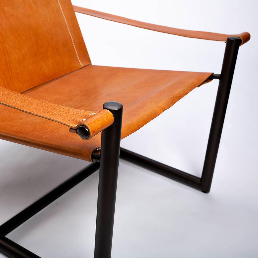Pipe lounge chair with thick saddle leather strapped to striking metal frame, closed up front view.