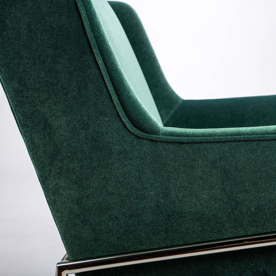 Green fabric Twiggy lounge chair with elegant leg detail in polished steel. Closed up side view.