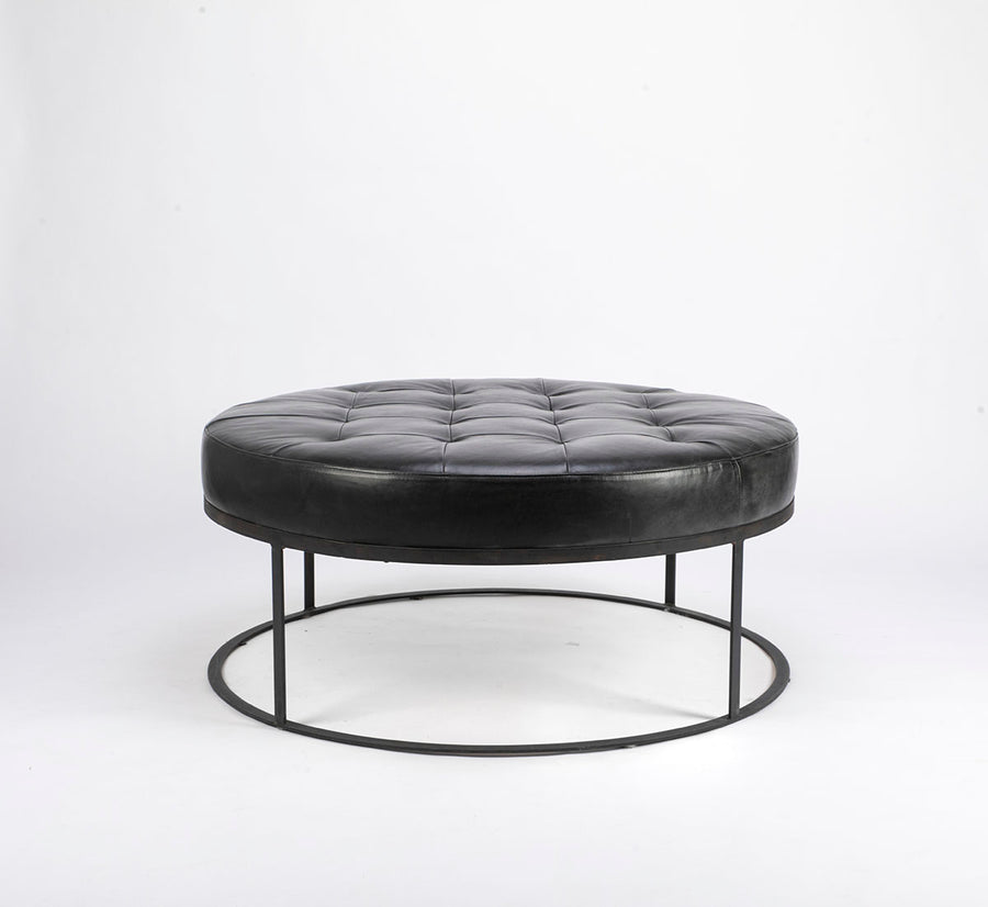 Tufted round ottoman by Cisco Brothers in top navy leather.