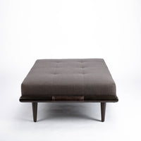Chatfield Ottoman in Tupelo graphite with a wood base.