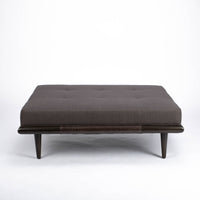 Chatfield Ottoman in Tupelo graphite with a wood base. Front view.