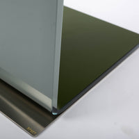 Two-toned bent glass coffee table with glued mat stainless steel plate. Closed up view on a steel plate.