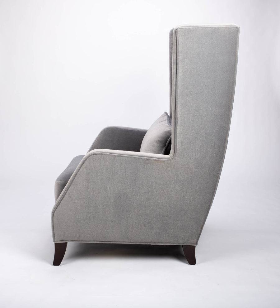 A light grey Rob lounge chair with extra high back, subtle angles and clean shape in the wing detail, side view.