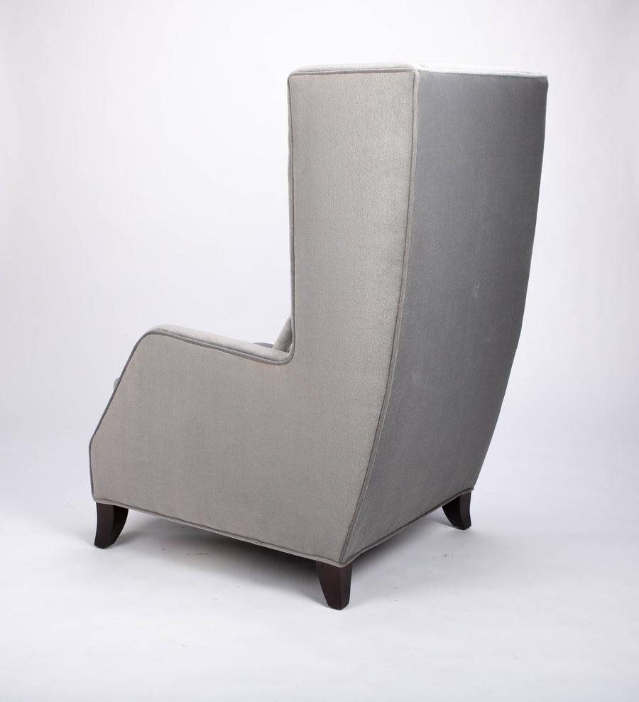 A light grey Rob lounge chair with extra high back, subtle angles and clean shape in the wing detail, side and back view.