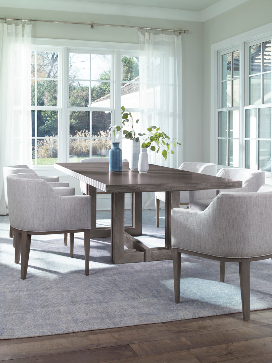 Axis Dining Table placed in a modern dining room with 6 white chairs and 3 vases with flowers on top of it.