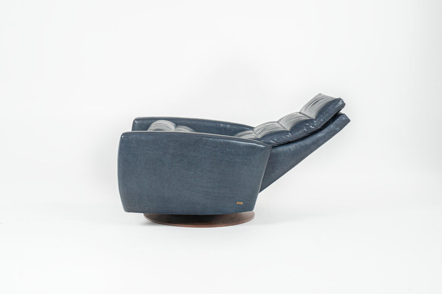 A blue Lanier leather recliner chair with the shape of classic automotive designs, reclined, side view.