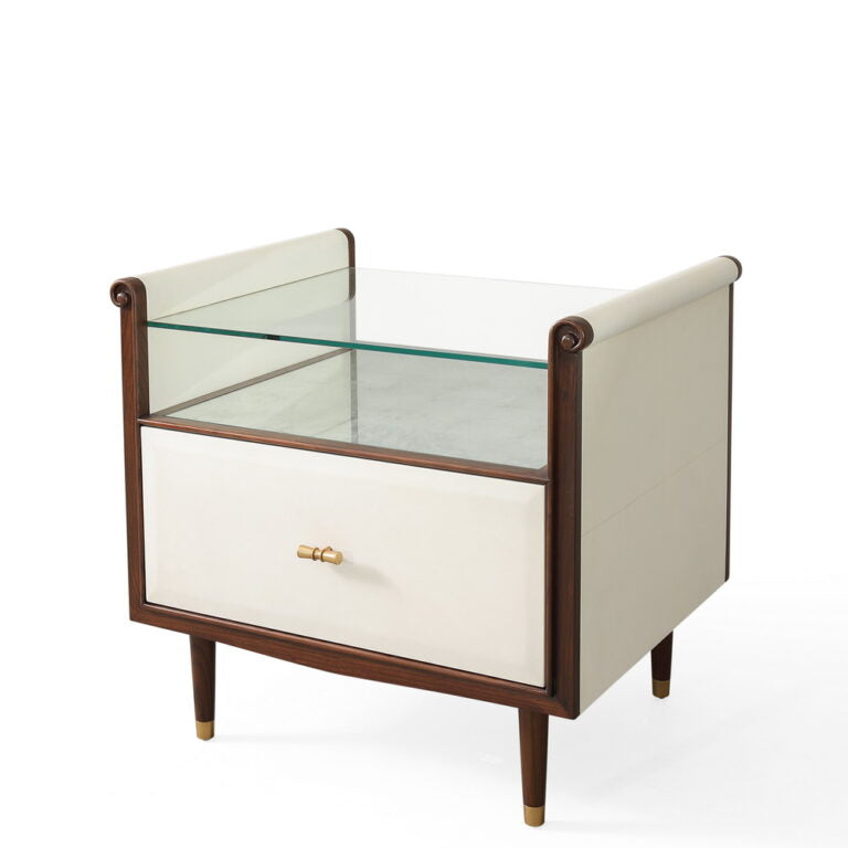Hepburn Bedside - single drawered Vellum clad bedside table with Rosewood legs and Aged Brass detail. Has a top with scrolled sides, which supports a toughened glass top that rests above an Verre Eglomise insert, front and side view.