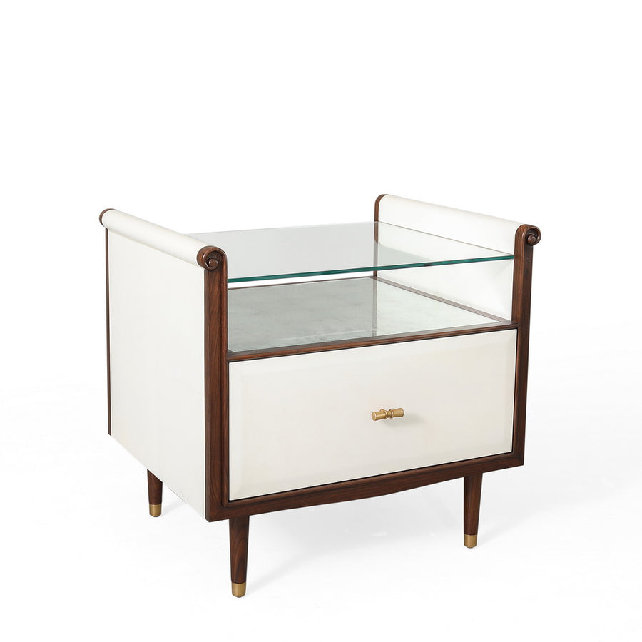 Hepburn Bedside - single drawered Vellum clad bedside table with Rosewood legs and Aged Brass detail. Has a top with scrolled sides, which supports a toughened glass top that rests above an Verre Eglomise insert.