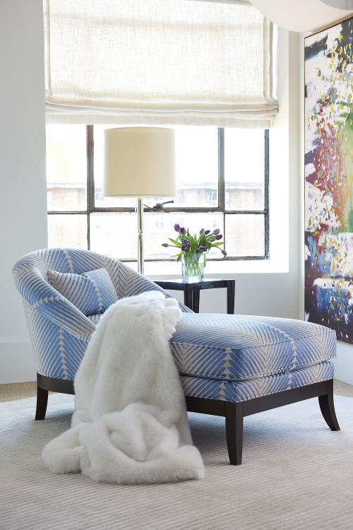 Lisette Chaise in light blue and white colors, placed in  a room with white blanket on it.