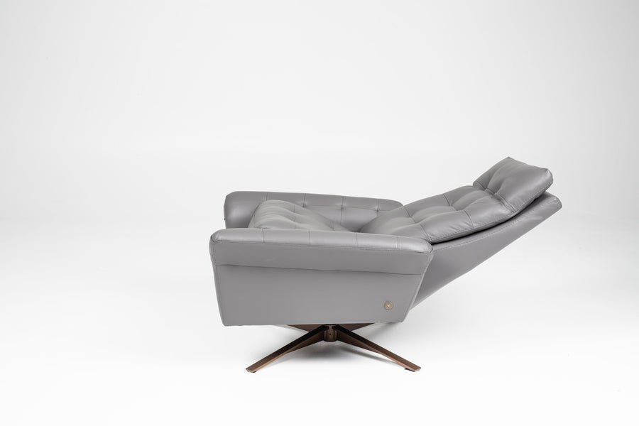 A grey leather recliner chair with buttonless tufted back and seat and four star base, side view, reclined.