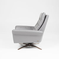 A grey leather recliner chair with buttonless tufted back and seat and four star base, side view.