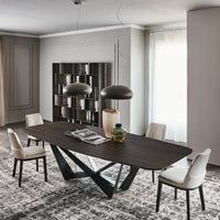 Wide Skorpio Dining Table with wooden top and origami based black base. Placed in a modern room with four white dining chairs.