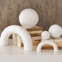 White Germain Arch Collection that consists of two different sized arches. Placed on a white table with antique books and three white decorative balls.