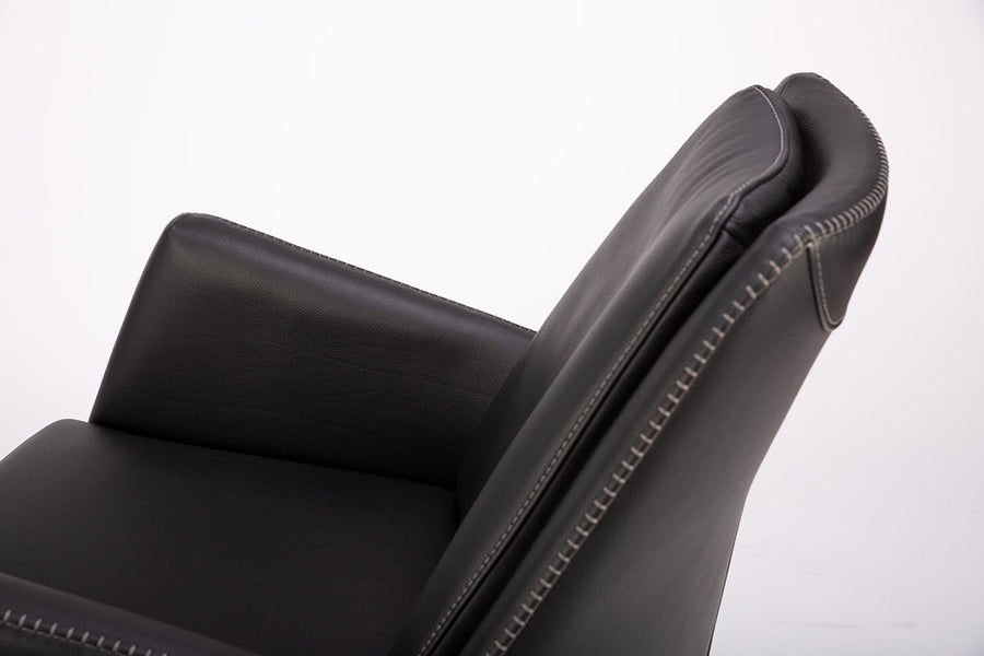 A black leather Kate swivel armchair. Closed up side view.