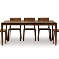 Lisse Extension dining table crafted in solid American black walnut hardwood with natural finish and with a single self-storing butterfly leaf for single handed operation. Shown with five matching chairs around it.