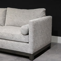 Grey two seat Oscar Sofa that features a slim tuxedo style, foam and down seats, arm bolsters and parson legs. Closed up side view.