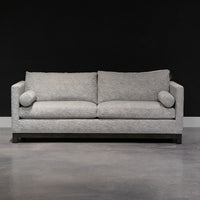 Grey two seat Oscar Sofa that  features a slim tuxedo style, foam and down seats, arm bolsters and parson legs. Front view.