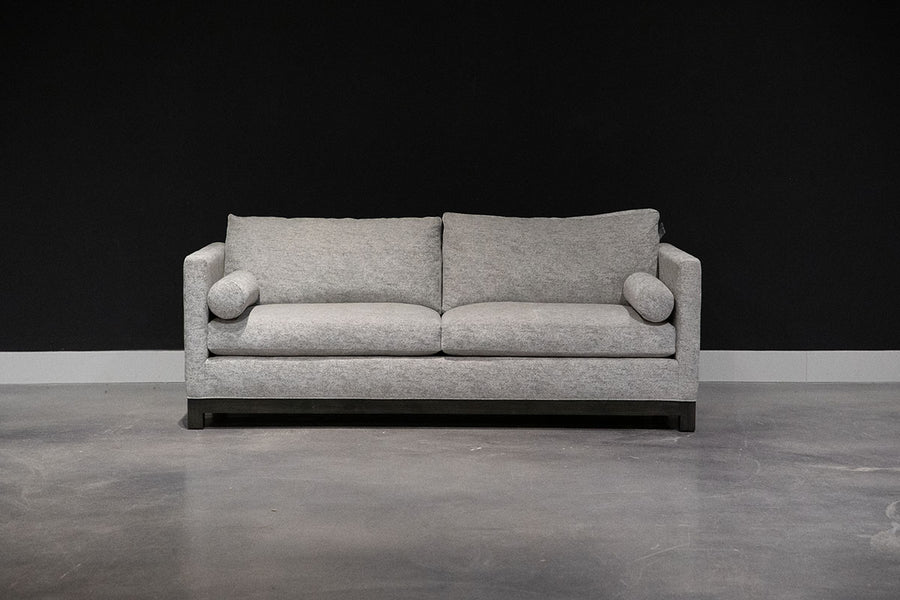 Grey two seat Oscar Sofa that  features a slim tuxedo style, foam and down seats, arm bolsters and parson legs. Front view.