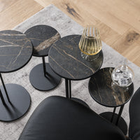 Collection of four black side tables with a drink on one of them and an ice on other.