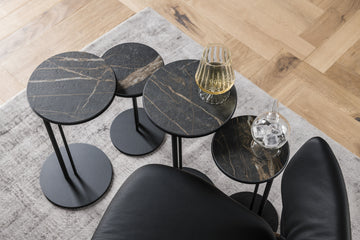 Collection of four black side tables with a drink on one of them and an ice on other.