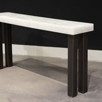 Modern console table with white top and black legs, side front view.