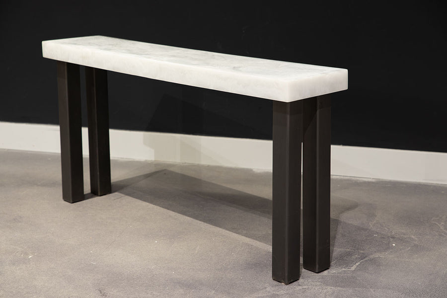 Modern console table with white top and black legs, side front view.