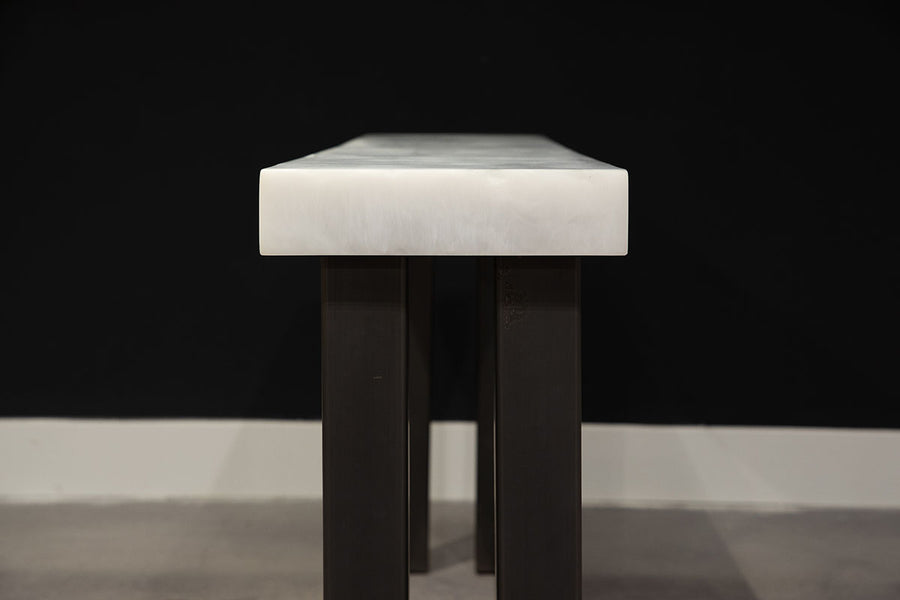 Modern console table with white top and black legs, side view.