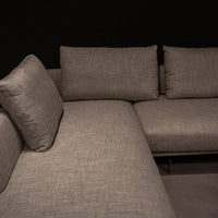 Light grey Quinta Strada Sectional with black chrome finish of the feet, the thinner joining clamps, and light base and back support. Closed up side view.