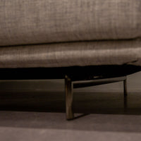 Light grey Quinta Strada Sectional with black chrome finish of the feet, the thinner joining clamps, and light base and back support. Closed up bottom view.