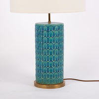 Eliot table lamp with white shade, blue & green wave pattern body with brass accents embellishing the base. Closed up view on the body and the base.