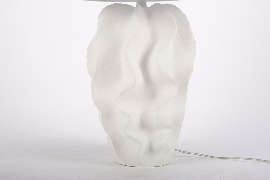 White Bethany Table Lamp with undulating curves of textured resin cascading into an urn shape. Closed up view on the stand.