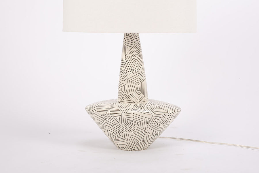 Toronto table lamp with white drum shade and geometric black design that contrasts the ivory ceramic gloss creating an unusually artful combination.