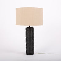 Mimi lamp with a beige linen shade and mate-black body with dimensional carving pattern.
