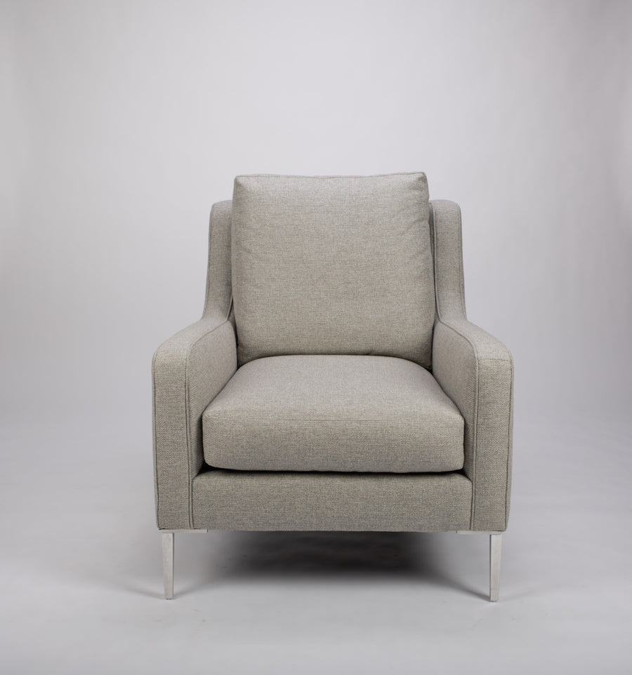 A light grey mid size lounge chair with classic shape and white legs. Front view.