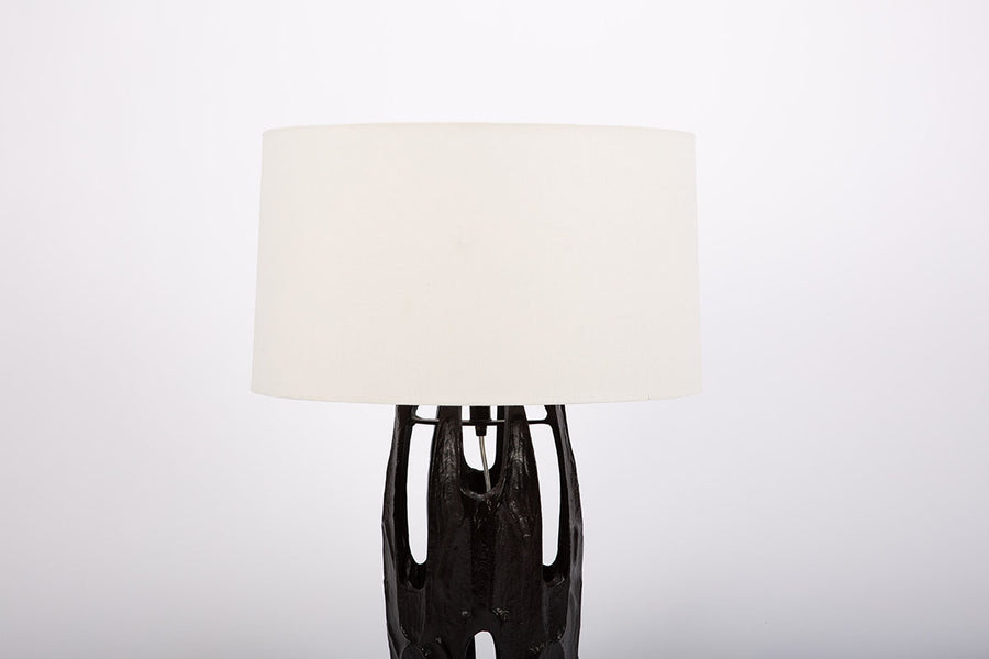 Naomi Lamp with an off-white linen drum shade and the black body done in the Brutalist style characterized by abstracted organic forms with rough textures