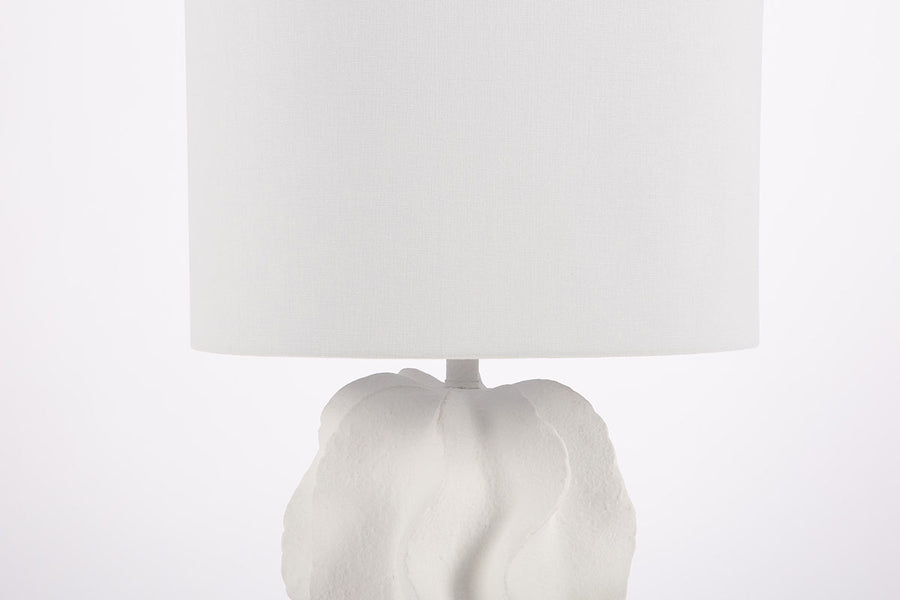 White Bethany Table Lamp with undulating curves of textured resin cascading into an urn shape. Closed up partial view on the stand and shade.