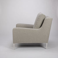 A light grey mid size lounge chair with classic shape and white legs. Side view.