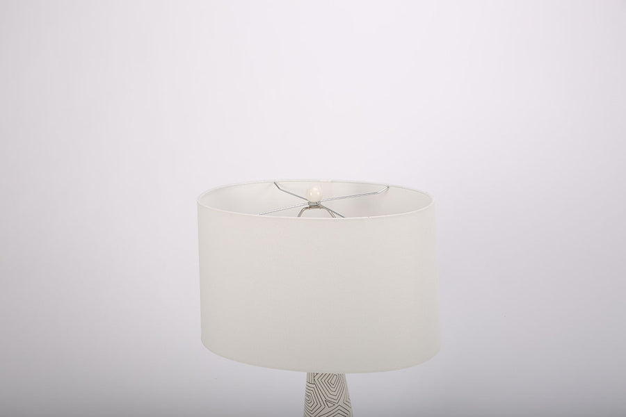 Toronto table lamp with white drum shade and geometric black design that contrasts the ivory ceramic gloss creating an unusually artful combination. 