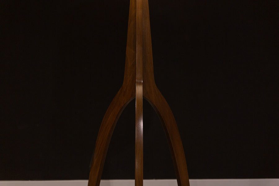 Linden Floor Lamp, a mid century adaptation with a tripod walnut base accented with brushed nickel foot caps and off white linen shade. Closed up view on the tripod base.